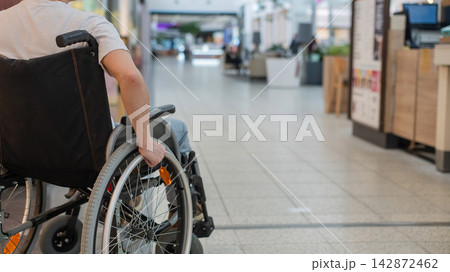 A Caucasian woman in a wheelchair shopping at a mall.  142872462