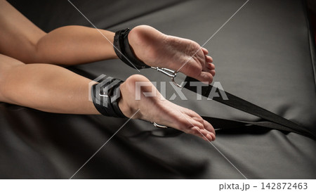 Women's legs in leather shackles. BDSM fetish. Women's legs in leather shackles. BDSM fetish. 142872463