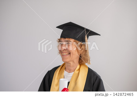 Happy senior woman in graduation gown holding diploma on white background. Happy senior woman in graduation gown holding diploma on white background. 142872465