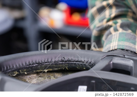 The mechanic changes the cover on the car steering wheel. The mechanic changes the cover on the car steering wheel. 142872569