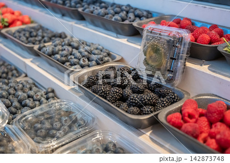 A counter with berries in a store. Raspberries, blackberries, and blueberries. A counter with berries in a store. Raspberries, blackberries, and blueberries. 142873748