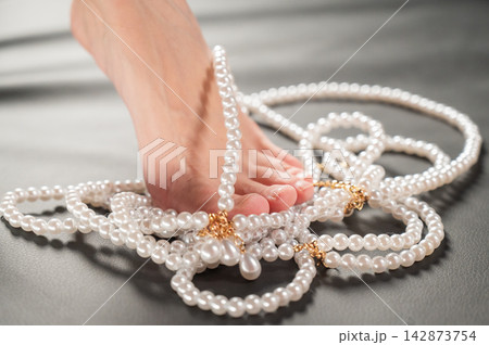 Foot fetish. Bare female feet with pearl beads. Foot fetish. Bare female feet with pearl beads. 142873754