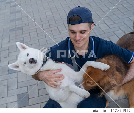 A man hugs his two dogs while on a walk. A man hugs his two dogs while on a walk. 142873917
