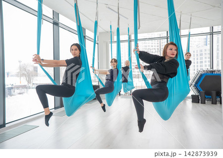Group yoga class on hammocks.  142873939