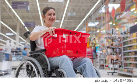 A Caucasian woman in a wheelchair shopping in a supermarket. A Caucasian woman in a wheelchair shopping in a supermarket. 142874089
