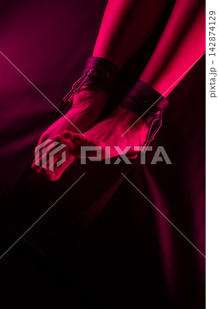Women's legs in leather shackles. BDSM fetish. Women's legs in leather shackles. BDSM fetish. 142874129