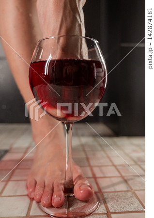 Foot fetish. A woman dips her toes in a glass of red wine. Foot fetish. A woman dips her toes in a glass of red wine. 142874181