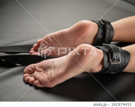 Women's legs in leather shackles. BDSM fetish. 142874452