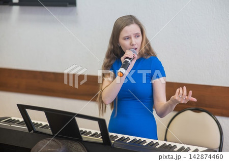 Caucasian woman singing into microphone. Caucasian woman singing into microphone. 142874460