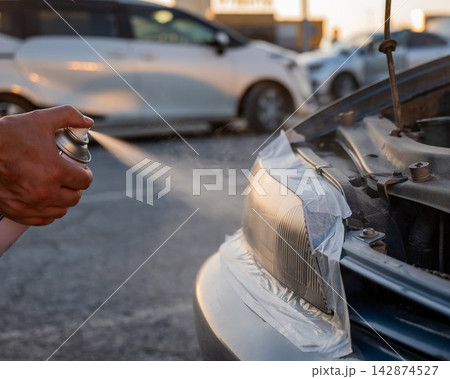 A man sprays headlights. The polishing process. A man sprays headlights. The polishing process. 142874527