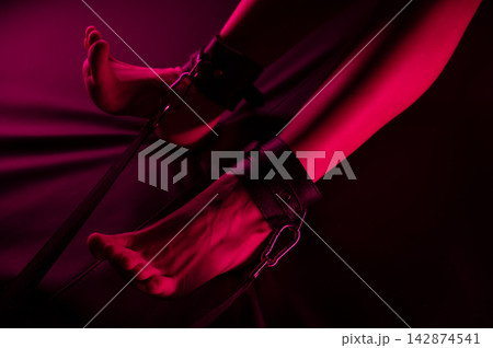 Women's legs in leather shackles. BDSM fetish. Women's legs in leather shackles. BDSM fetish. 142874541