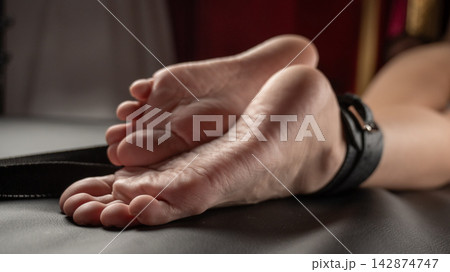 Women's legs in leather shackles. BDSM fetish. Women's legs in leather shackles. BDSM fetish. 142874747