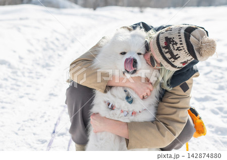 Portrait of a Caucasian woman hugging her Samoyed dog during a winter walk.  142874880