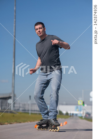 A Caucasian man rollerblades around the slalom course. A Caucasian man rollerblades around the slalom course. 142874936