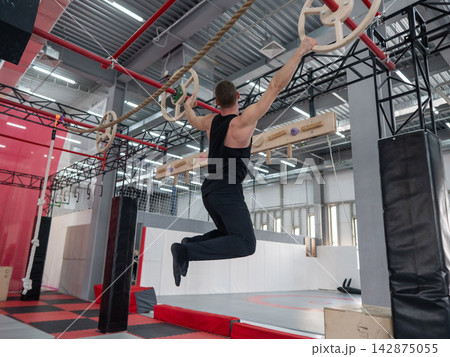 An athletic man practices at a ninja club's indoor obstacle course. An athletic man practices at a ninja club's indoor obstacle course. 142875055