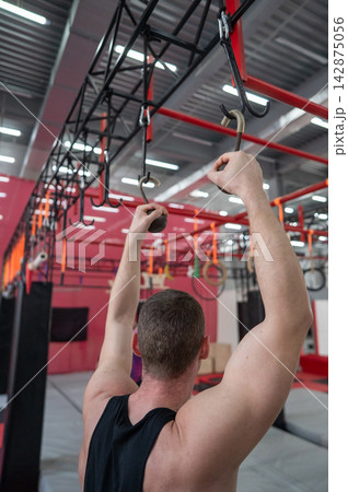 An athletic man practices at a ninja club's indoor obstacle course. An athletic man practices at a ninja club's indoor obstacle course. 142875056