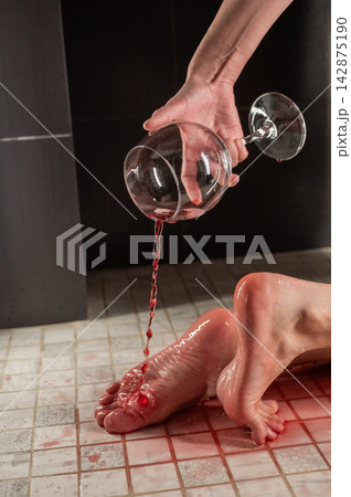 Foot fetish. A woman pours wine from a glass onto her feet in the shower. 142875190