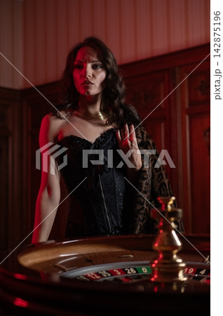 A beautiful brunette in a black dress at the casino roulette wheel. A beautiful brunette in a black dress at the casino roulette wheel. 142875196