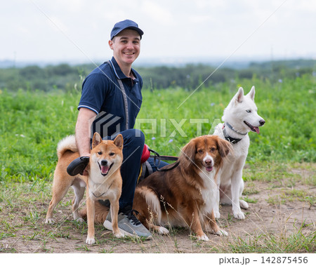 A Caucasian man walks with three dogs. Dog walker. A Caucasian man walks with three dogs. Dog walker. 142875456