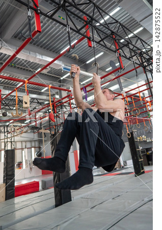 An athletic man practices at a ninja club's indoor obstacle course. 142875522