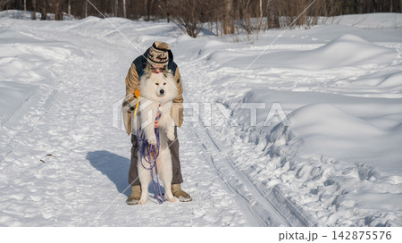 Smiling woman holding fluffy samoyed dog in snowy winter park. Smiling woman holding fluffy samoyed dog in snowy winter park. 142875576