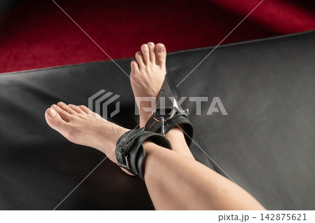 Women's legs in leather shackles. BDSM fetish. Women's legs in leather shackles. BDSM fetish. 142875621