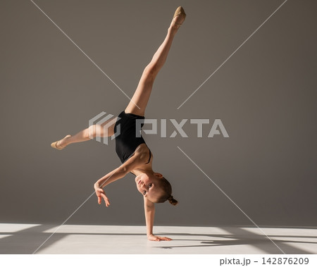 A little girl gymnast does a handstand. Copy space.  142876209