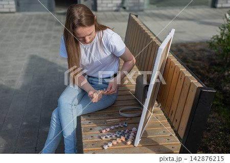 A Caucasian woman with mild cerebral palsy paints by numbers outdoors 142876215