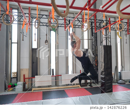 An athletic man practices at a ninja club's indoor obstacle course. An athletic man practices at a ninja club's indoor obstacle course. 142876226