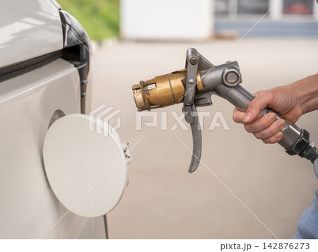 A woman fills a car with gas. Close-up of her hands. A woman fills a car with gas. Close-up of her hands. 142876273