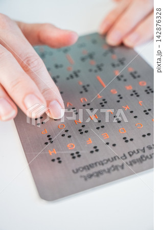 A blind woman learns the English alphabet from a braille sign. A blind woman learns the English alphabet from a braille sign. 142876328