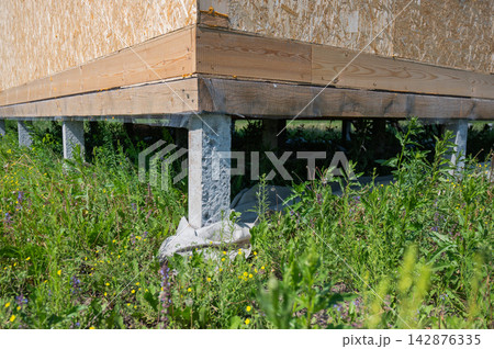 A close-up of concrete piles on a country house under construction. Cottage foundation. A close-up of concrete piles on a country house under construction. Cottage foundation. 142876335