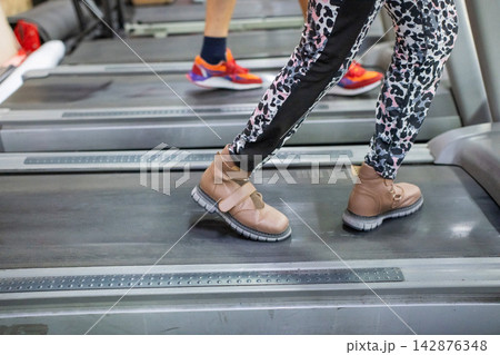A woman with cerebral palsy walks on a treadmill.  142876348
