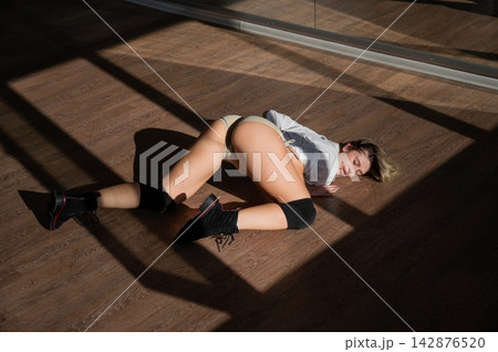 A young woman dances twerk in short shorts on the floor. A young woman dances twerk in short shorts on the floor. 142876520