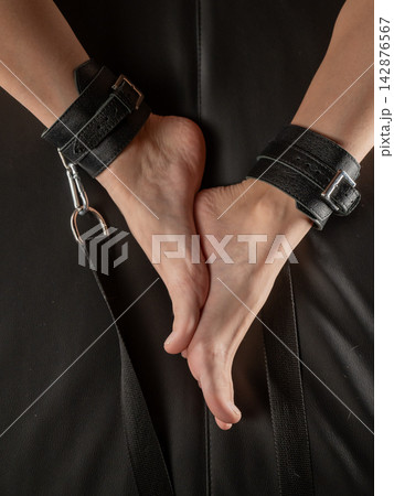 Women's legs in leather shackles. BDSM fetish. Women's legs in leather shackles. BDSM fetish. 142876567