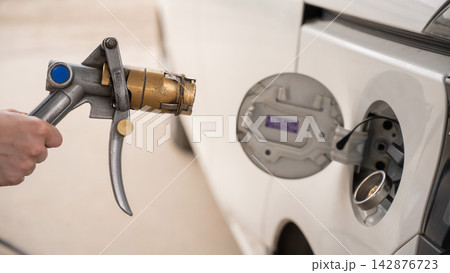 A woman fills a car with gas. Close-up of her hands. A woman fills a car with gas. Close-up of her hands. 142876723