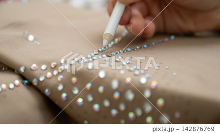 A woman decorates her gymnastics costume with rhinestones. Rhythmic gymnastics.  142876769