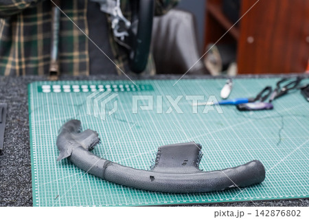 The mechanic changes the cover on the car steering wheel. The mechanic changes the cover on the car steering wheel. 142876802