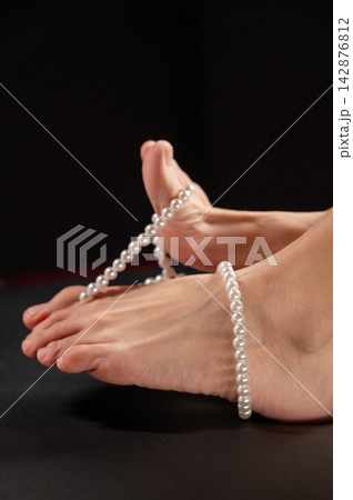 Foot fetish. Bare female feet with pearl beads. Foot fetish. Bare female feet with pearl beads. 142876812