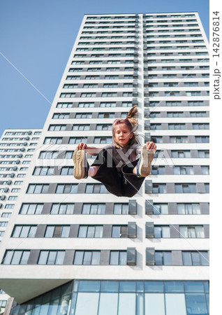 A girl jumps on an outdoor trampoline. 142876814