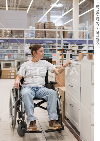 A Caucasian woman in a wheelchair buys furniture. A Caucasian woman in a wheelchair buys furniture. 142876838