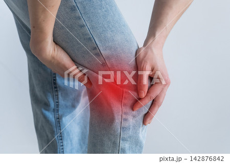 A Caucasian woman suffers from knee pain. The location of the pain is shown as a red spot. 142876842
