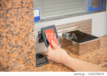 A woman pays for a ride with a bank card at a metro ticket office. 142876874