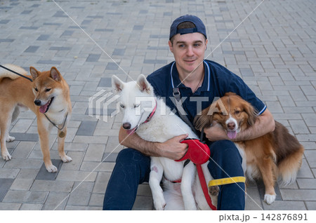 A man hugs his two dogs while on a walk.  142876891