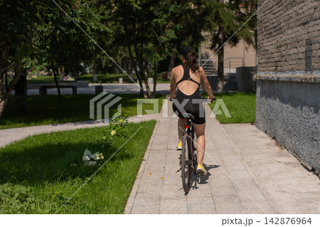A Caucasian woman riding a bicycle.  142876964