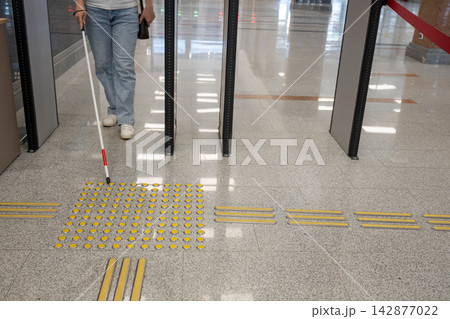 A blind woman walks through a metal detector. A blind woman walks through a metal detector. 142877022