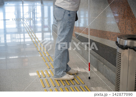 A blind woman buys a subway ticket. Close-up of legs. A blind woman buys a subway ticket. Close-up of legs. 142877090