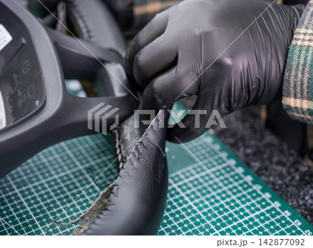 The mechanic changes the cover on the car steering wheel. The mechanic changes the cover on the car steering wheel. 142877092