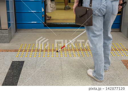 A blind woman enters a subway car. A blind woman enters a subway car. 142877120