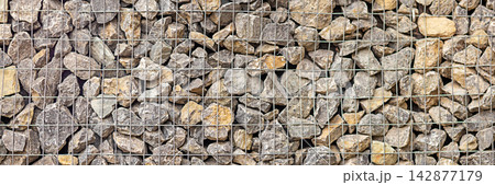 Gabion wall of natural stones in metal wire mesh for landscaping and erosion control Gabion wall of natural stones in metal wire mesh for landscaping and erosion control 142877179